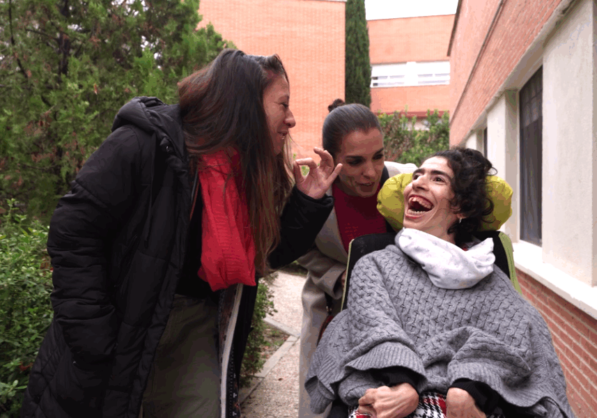 Una mujer con grandes necesidades de apoyo, acompañada por profesionales de su entidad.